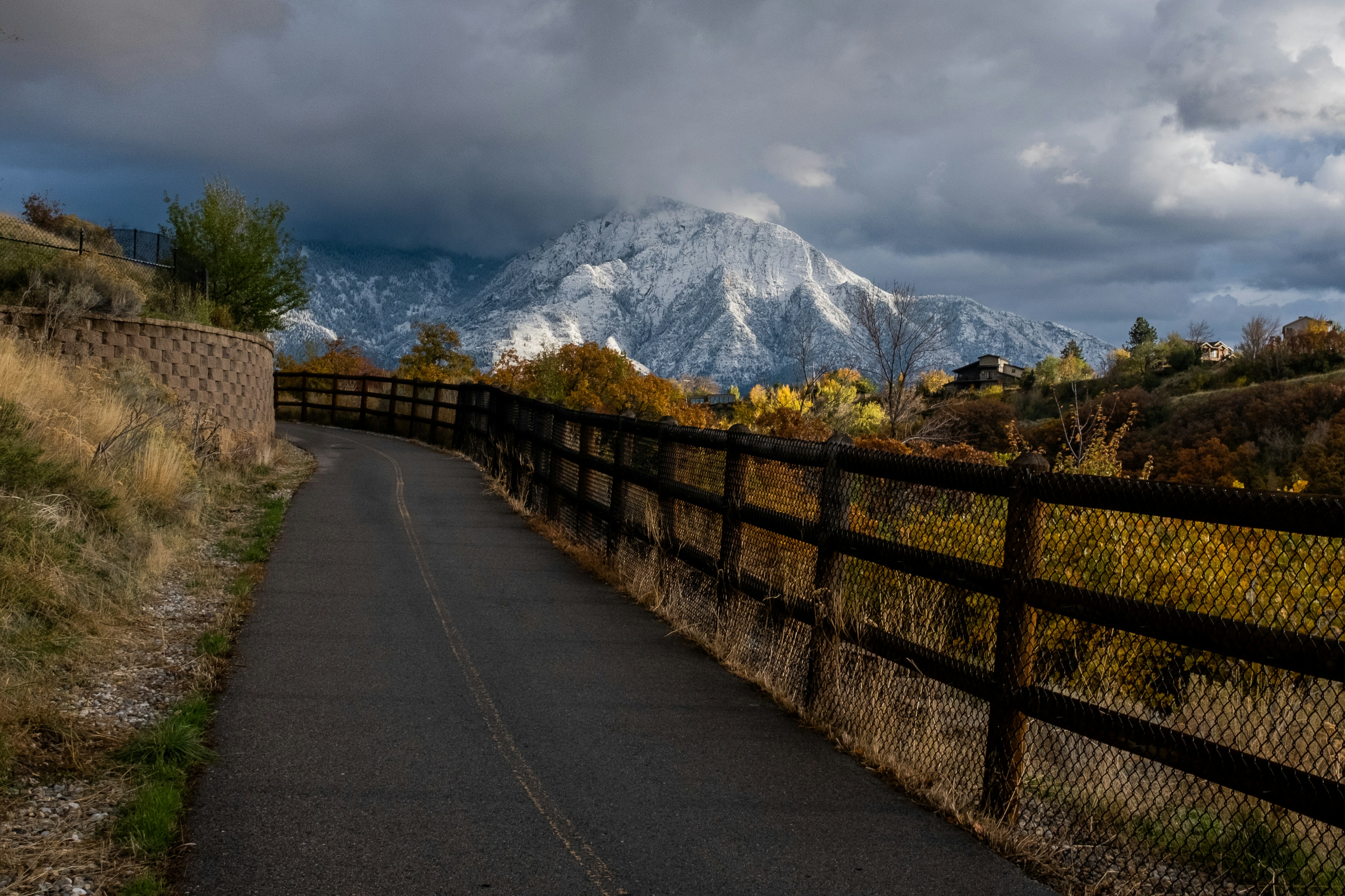 a road that is next to a fence with a mountain in the background