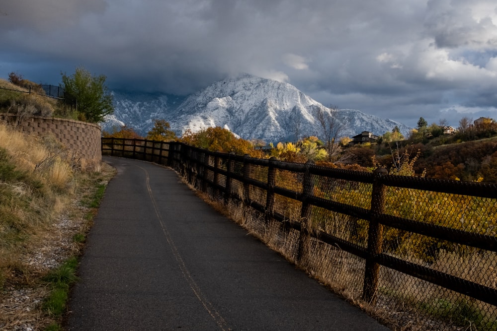 a road that is next to a fence with a mountain in the background