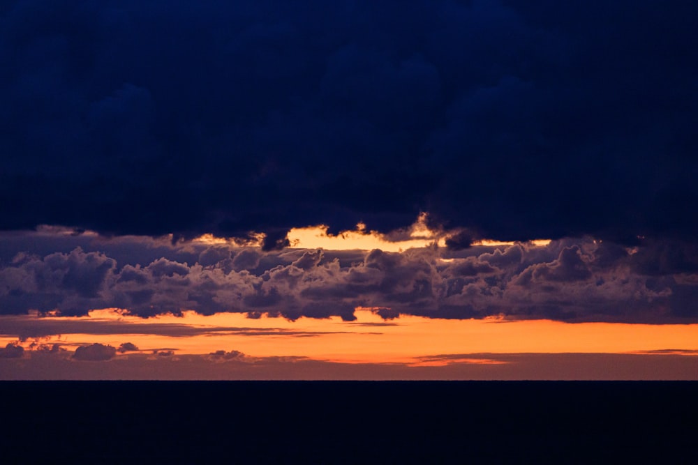 a plane flying through a cloudy sky at sunset