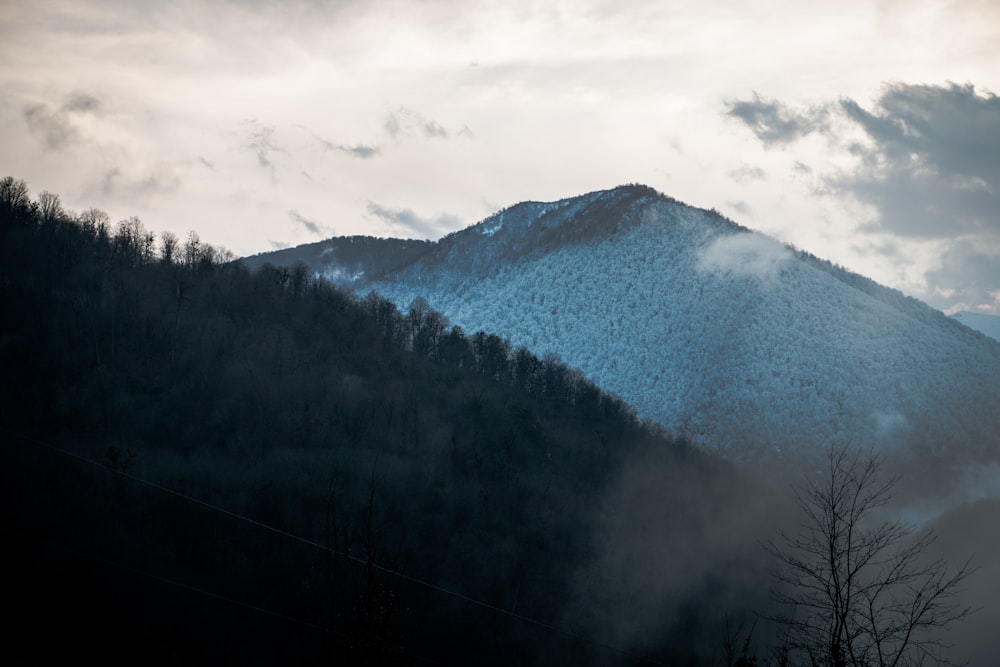 a mountain covered in snow and clouds under a cloudy sky