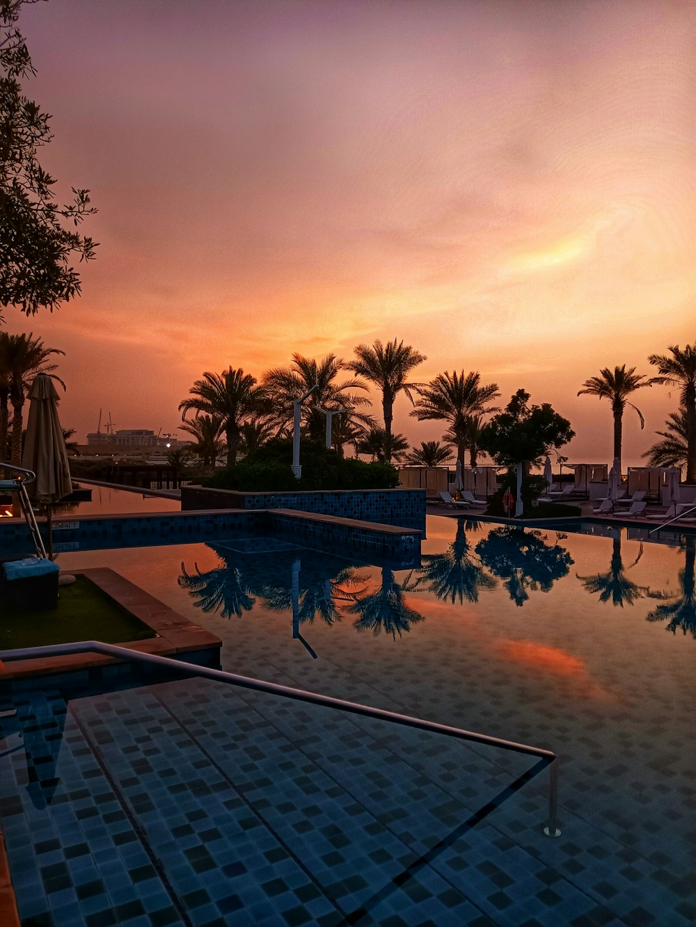 a swimming pool with a sunset in the background