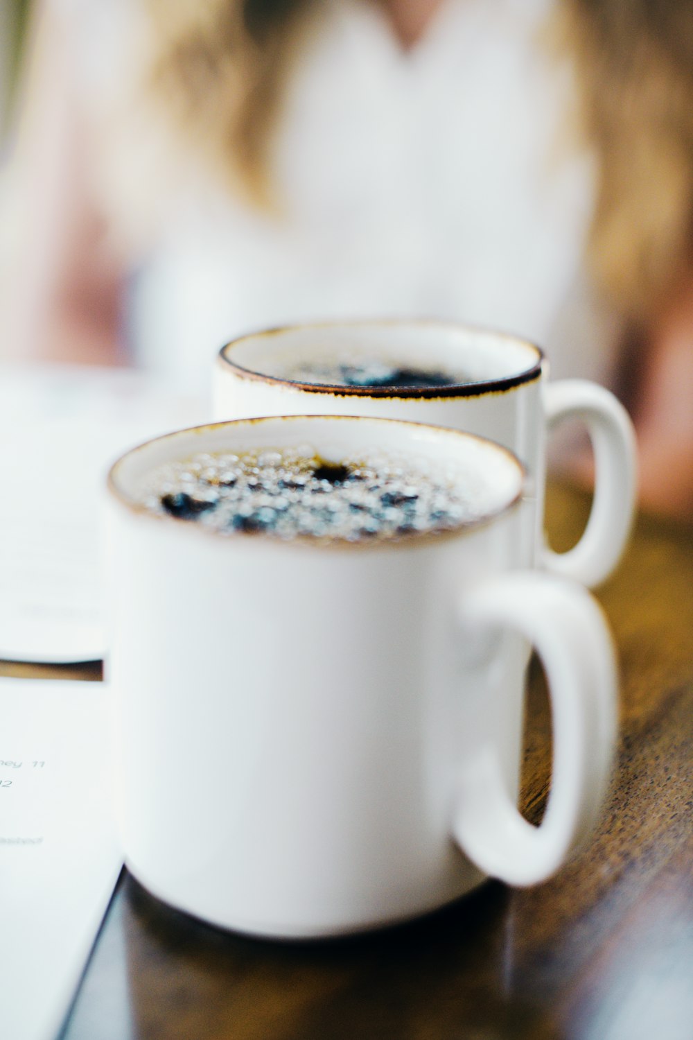 two cups of coffee sitting on top of a wooden table