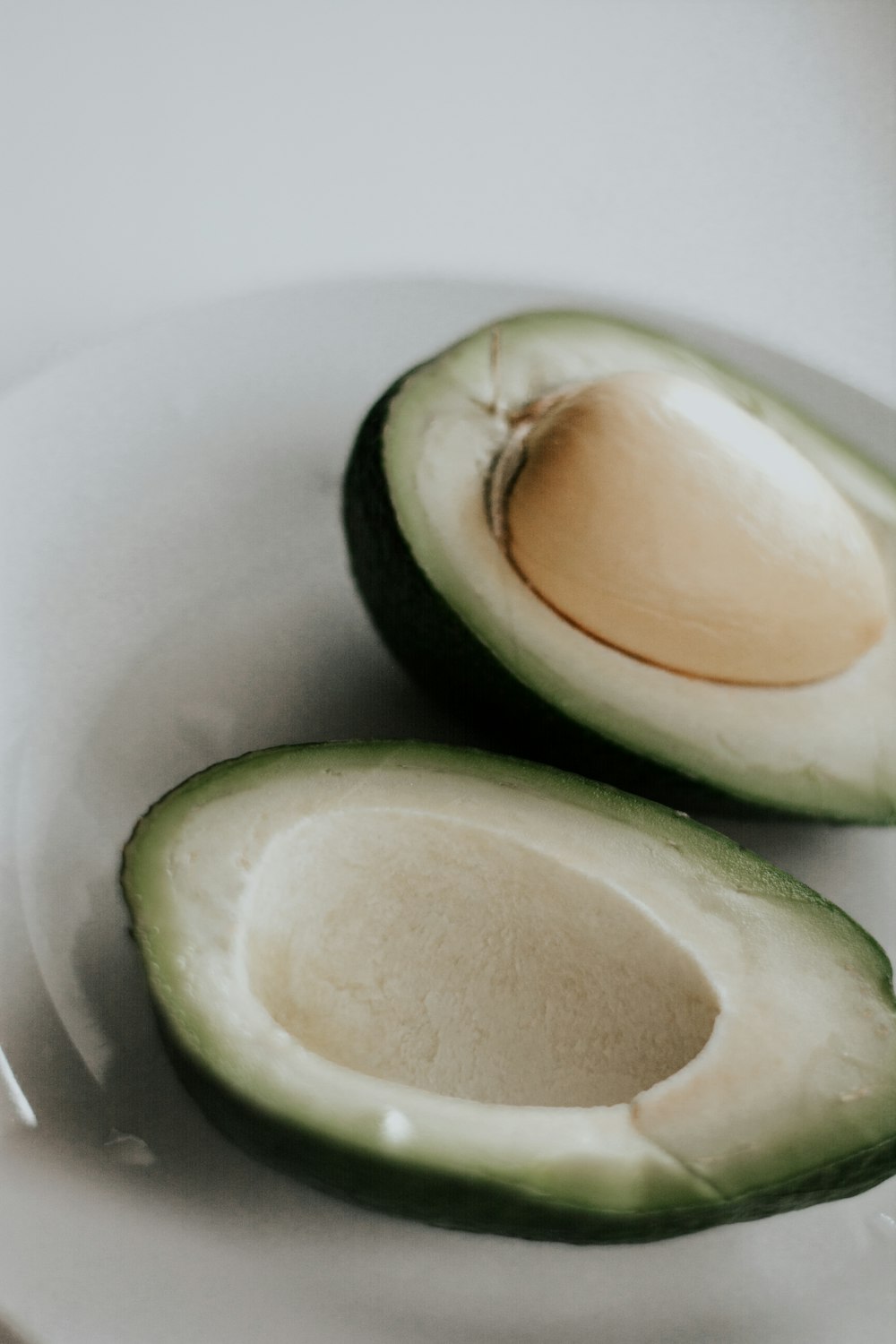 a white plate topped with an avocado cut in half