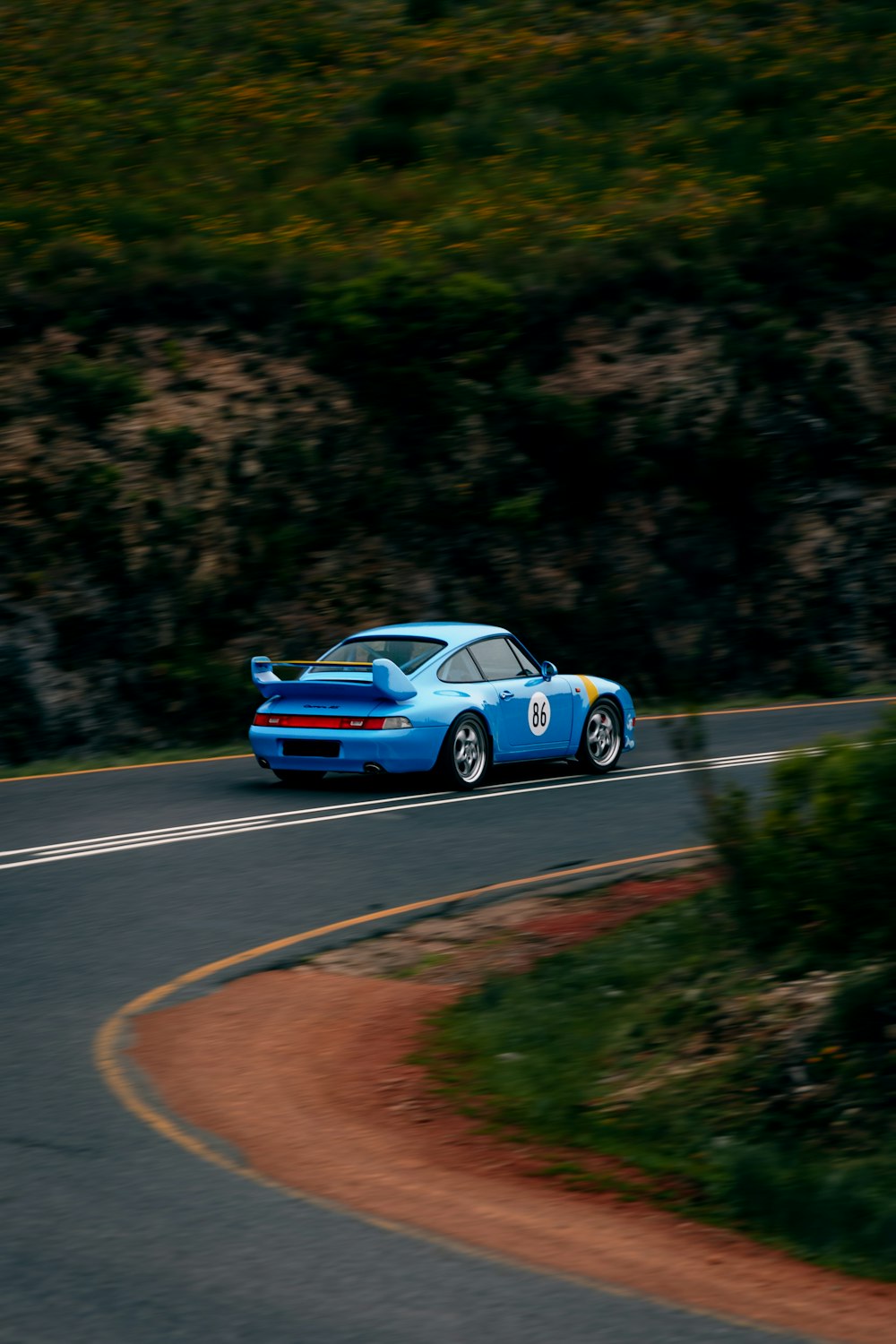 a blue sports car driving down a winding road