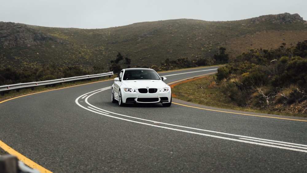 a white car driving down a curvy road