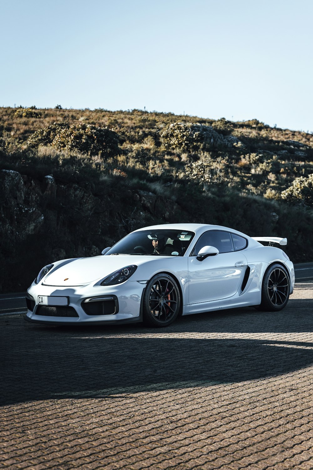 a white sports car driving down a road