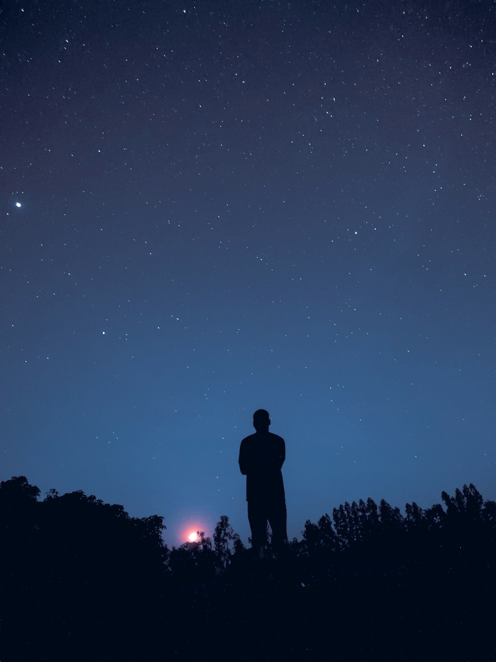 a man standing on top of a hill under a night sky