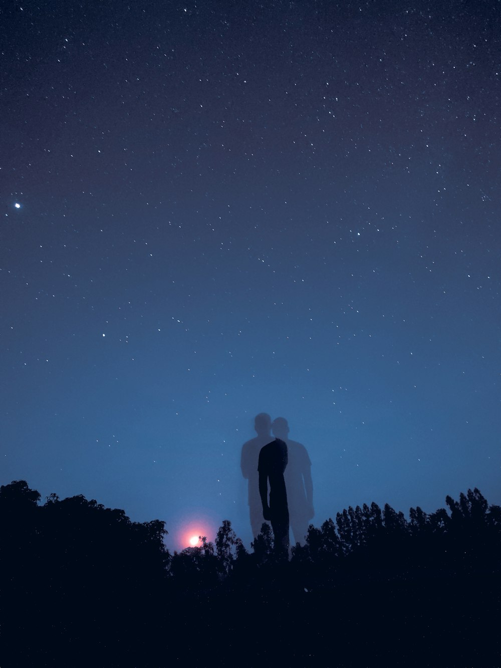 a couple of people standing next to each other under a night sky