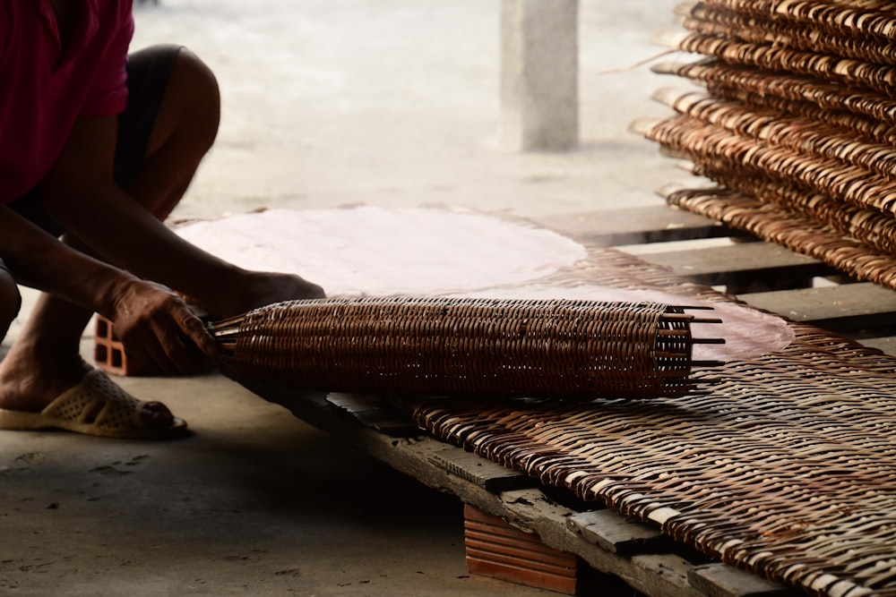 a person kneeling down next to a stack of wicker baskets