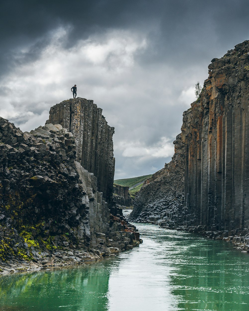 Un homme debout au sommet d’une falaise au bord d’une rivière