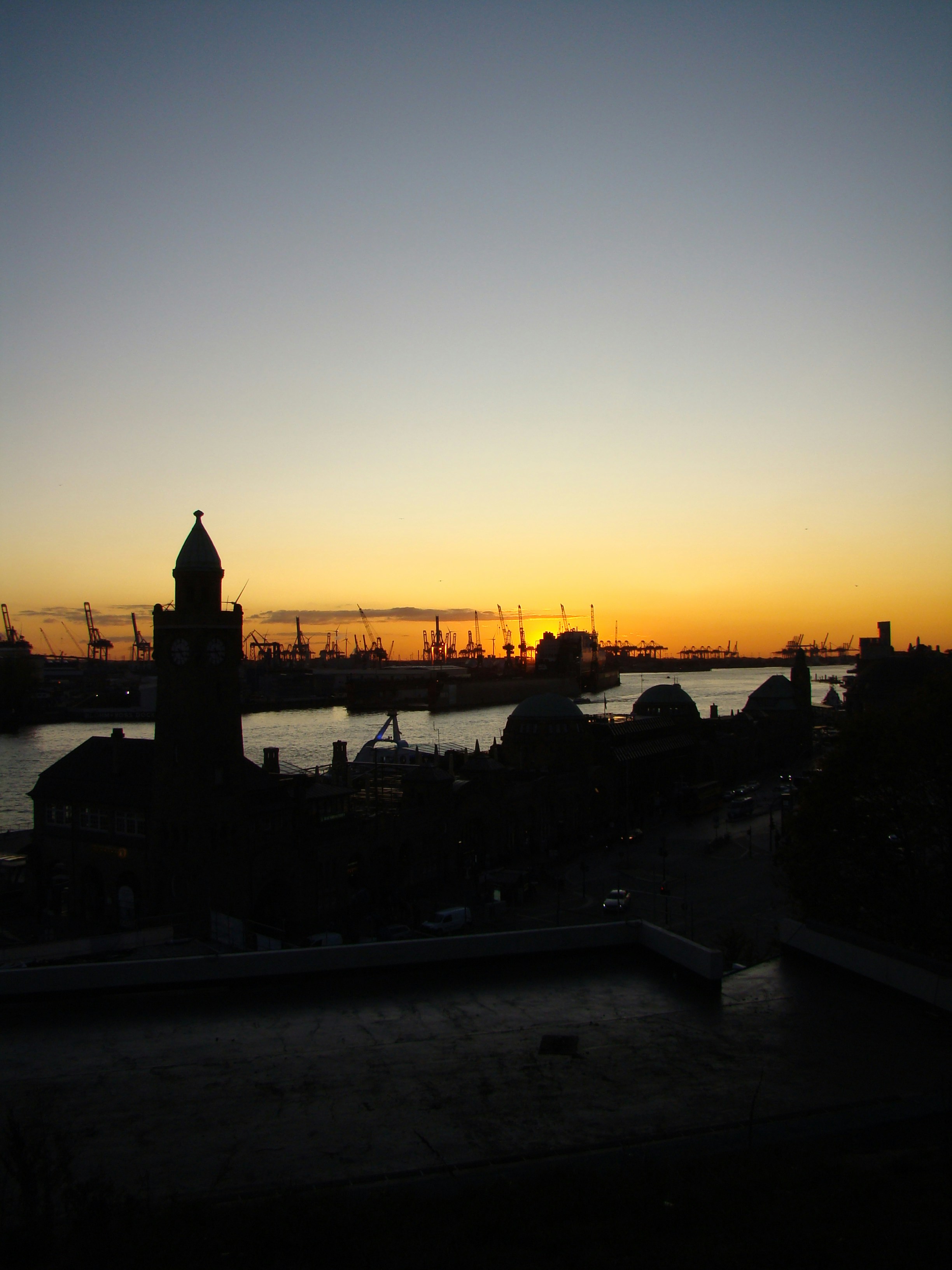 a sunset view of a harbor with a clock tower in the foreground