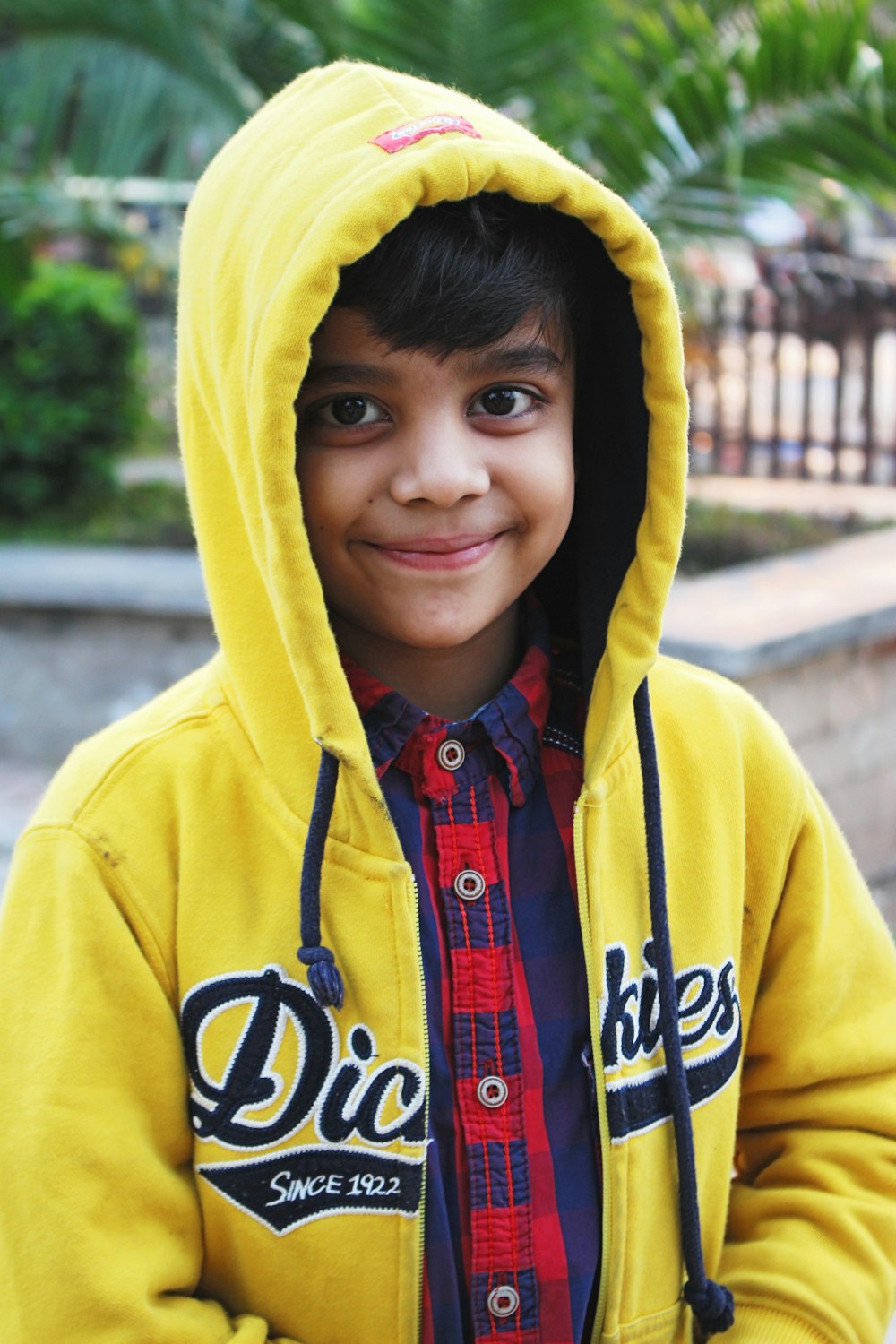 a young boy wearing a yellow sweatshirt and smiling