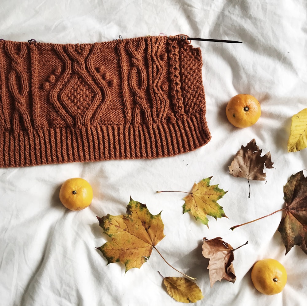 a brown knitted sweater surrounded by autumn leaves