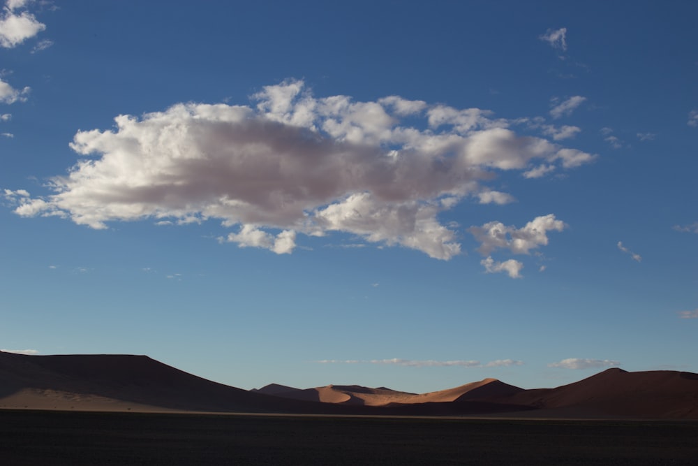 a large cloud is in the sky over a desert