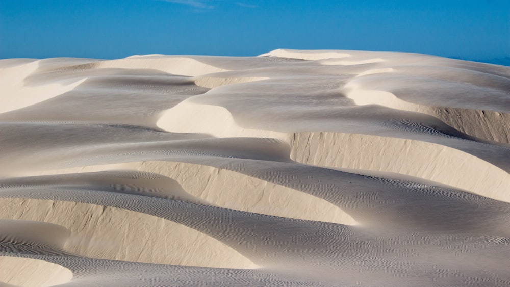 a group of sand dunes with a blue sky in the background