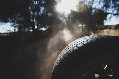 Close-up of a heavy-duty tire rolling over a dusty road, dust swirling in the golden light.
