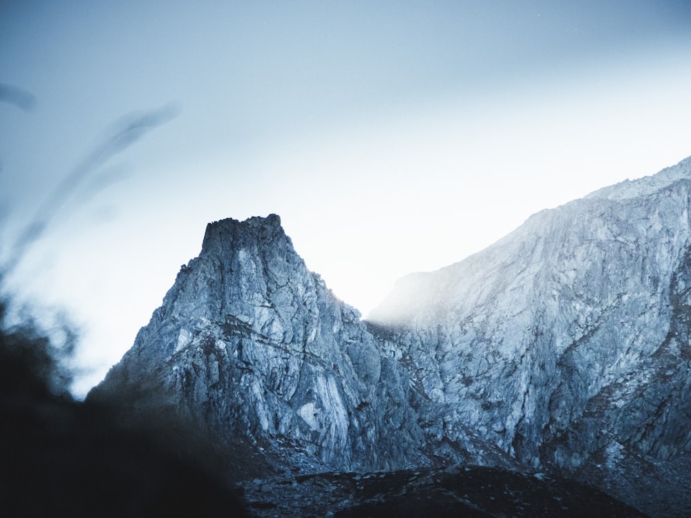 a very tall mountain covered in snow under a cloudy sky