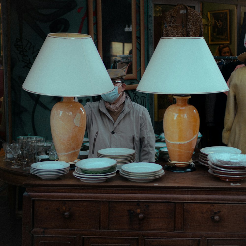 a man standing in front of a table with two lamps on it