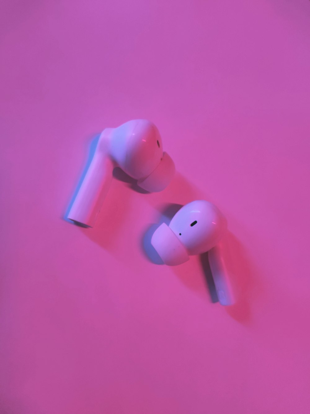 a pair of ear buds sitting on top of a pink surface