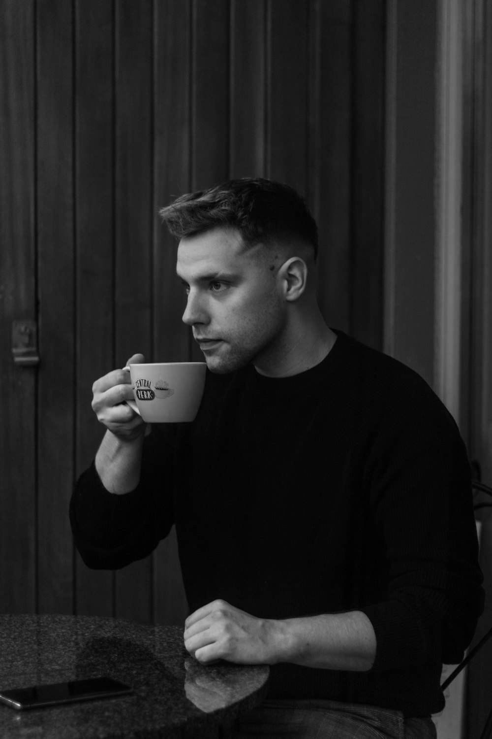a man sitting at a table holding a cup of coffee