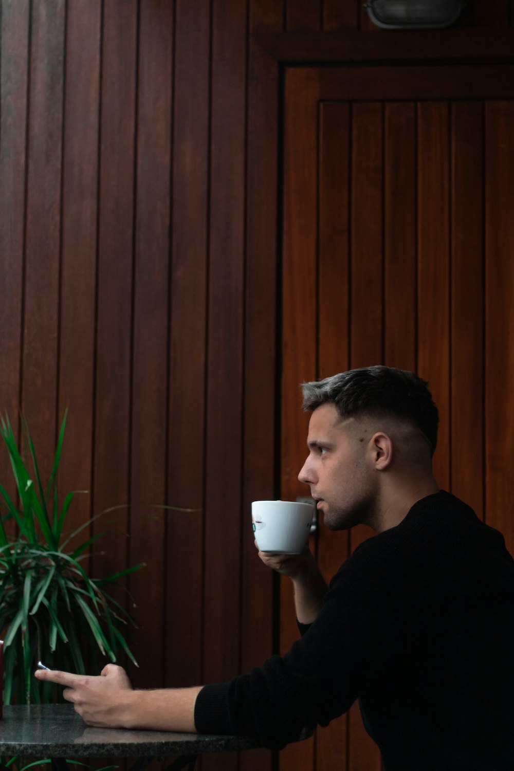 a man sitting at a table drinking a cup of coffee