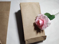 A stack of various sized custom paper bags with subtle logo prints arranged neatly on a wooden table.