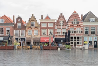 a row of brick buildings with tables and chairs in front of them