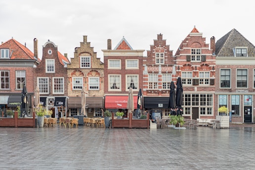 a row of brick buildings with tables and chairs in front of them