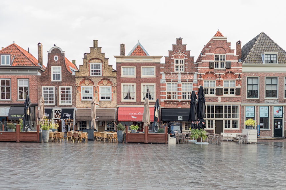 a row of brick buildings with tables and chairs in front of them