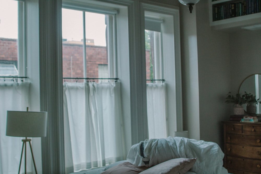 a bed with a white comforter and pillows in front of a window