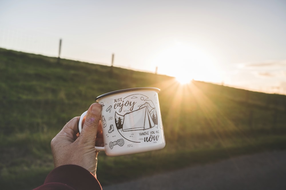 a person holding a coffee mug in their hand