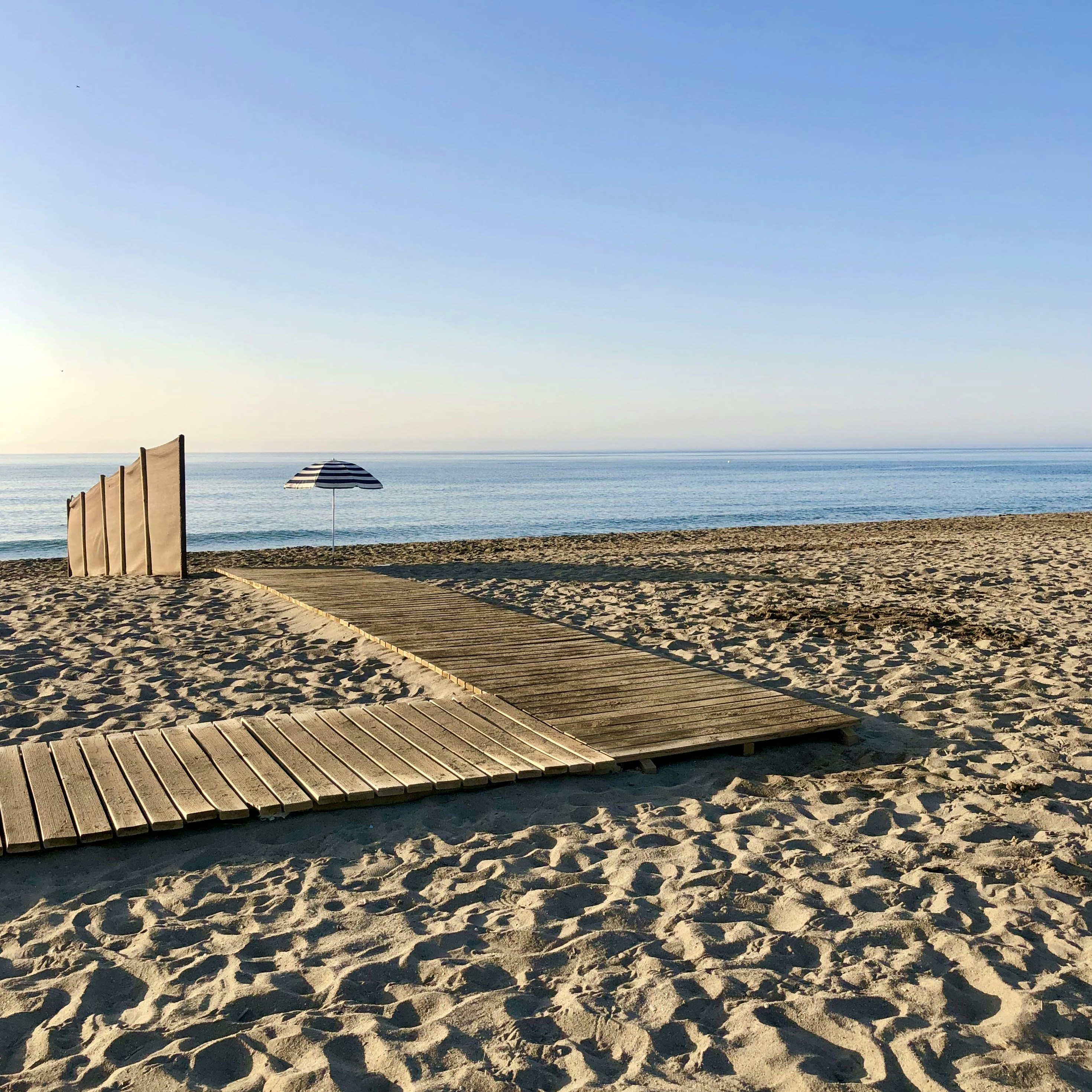 Une Passerelle En Bois Menant Une Plage Avec Un Parasol Photo Photo
