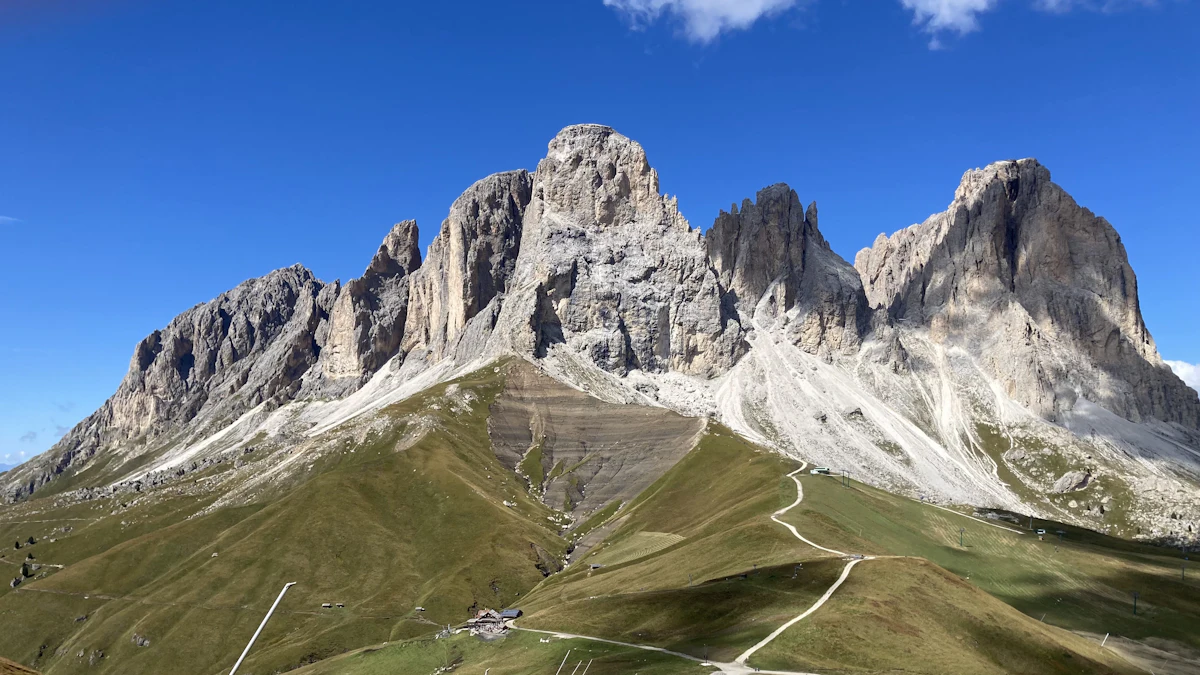 Pale Dolomite towers above green slopes crossed by gravel paths