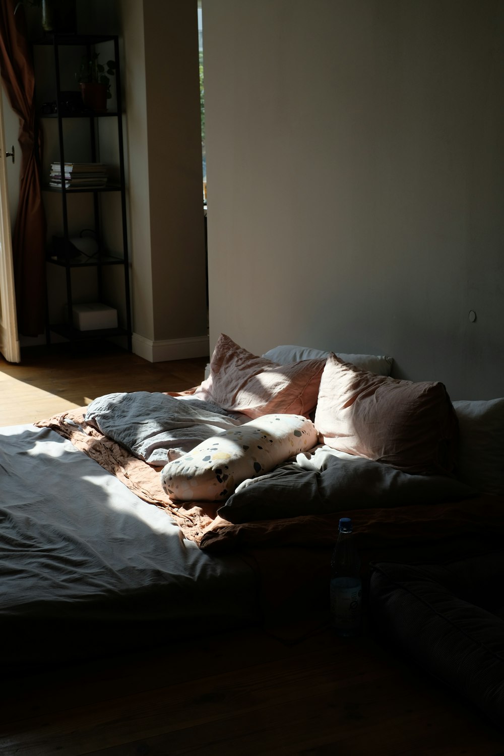 an unmade bed sitting in a bedroom next to a window