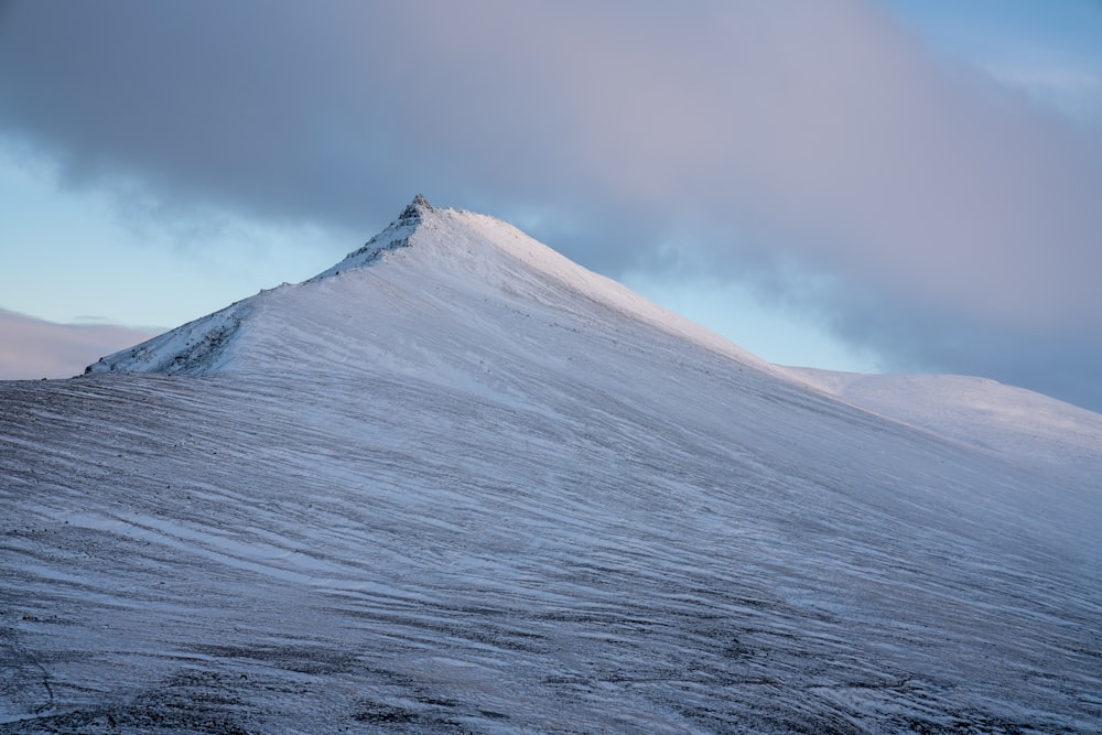 a mountain covered in snow under a cloudy sky