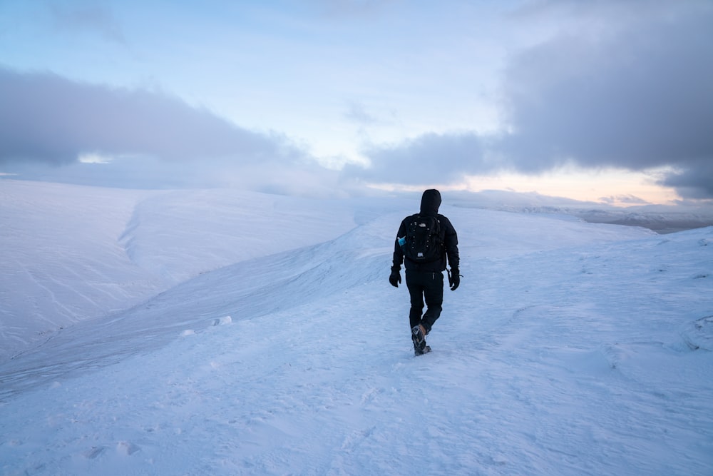 a man walking up a snow covered hill