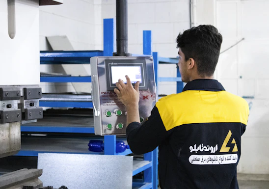 Technician programming an industrial PLC controller in a modern factory setting.