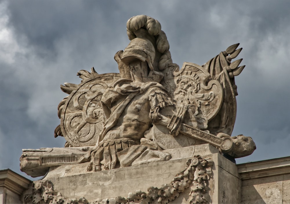 a statue on top of a building under a cloudy sky