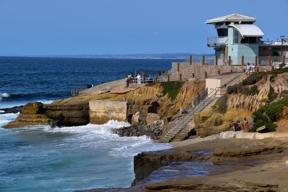 a house sitting on top of a cliff next to the ocean