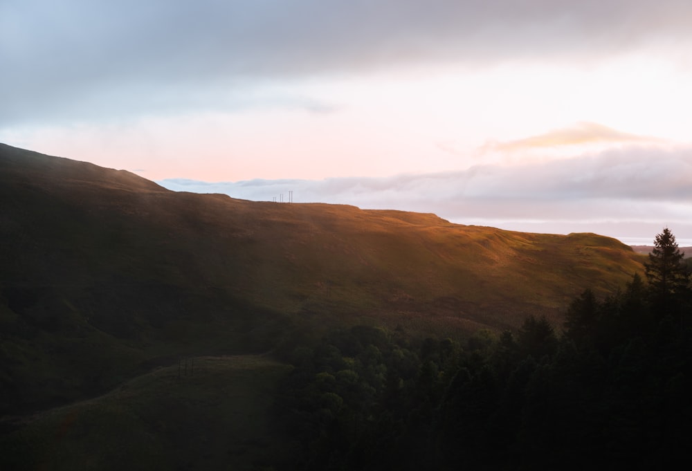 the sun is setting on a mountain with trees in the foreground