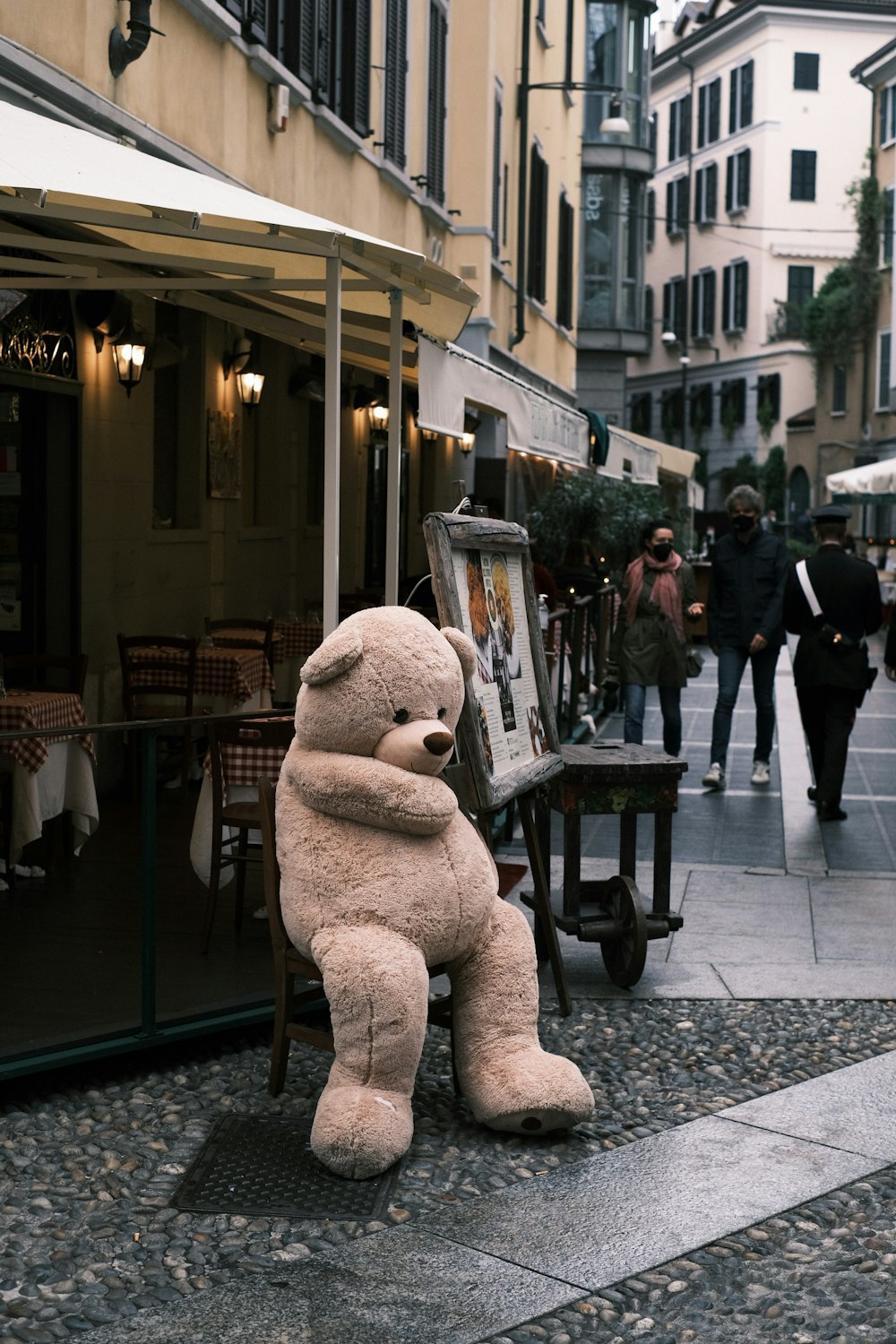 a large teddy bear sitting on the ground in front of a building
