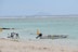 a boat sitting on top of a sandy beach next to the ocean