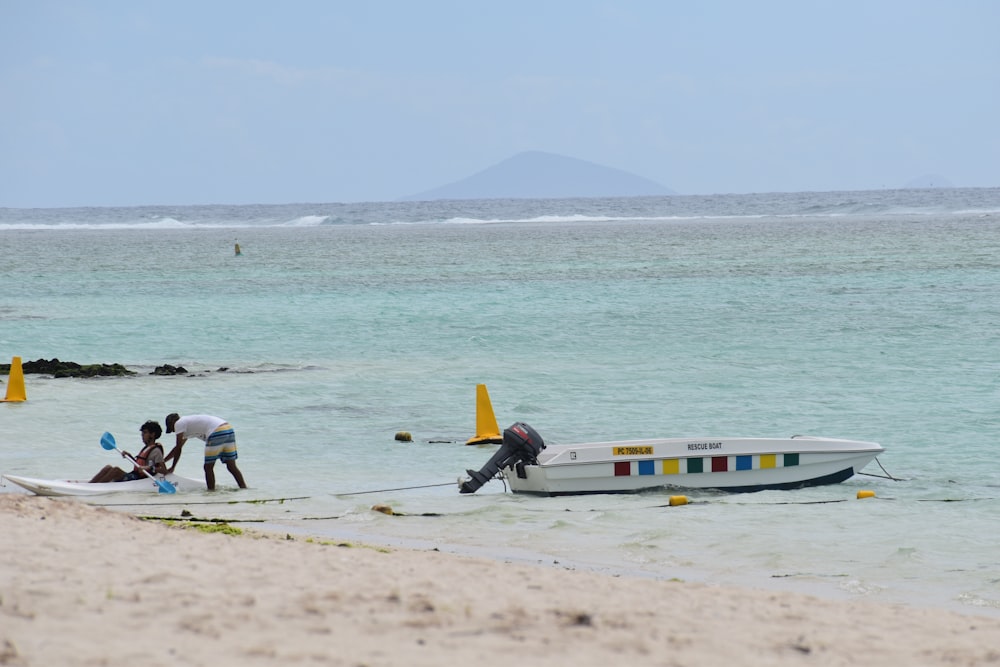 a boat sitting on top of a sandy beach next to the ocean