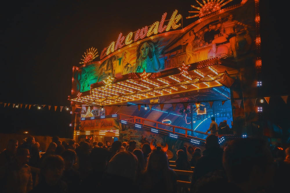 a crowd of people standing around a carnival ride at night