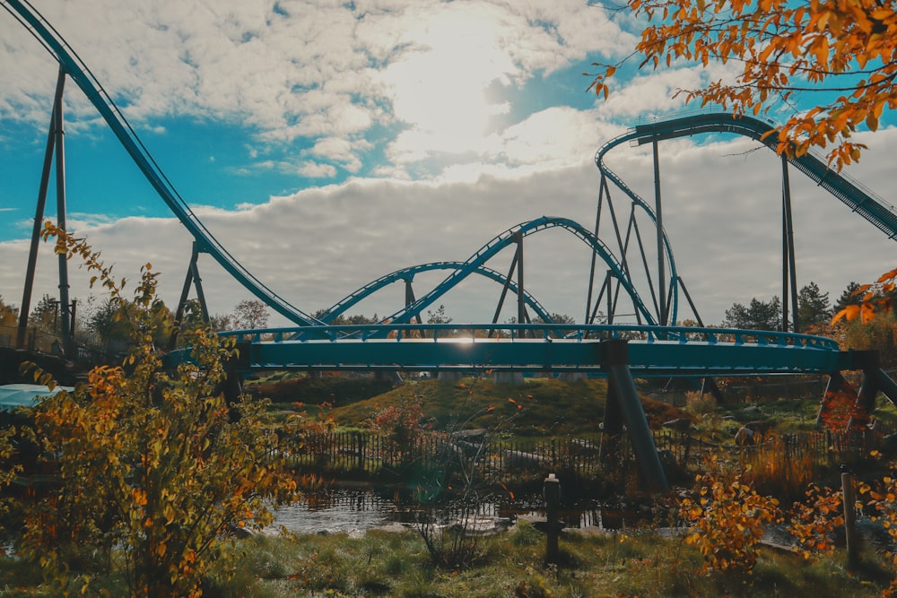 a roller coaster going over a river in a park