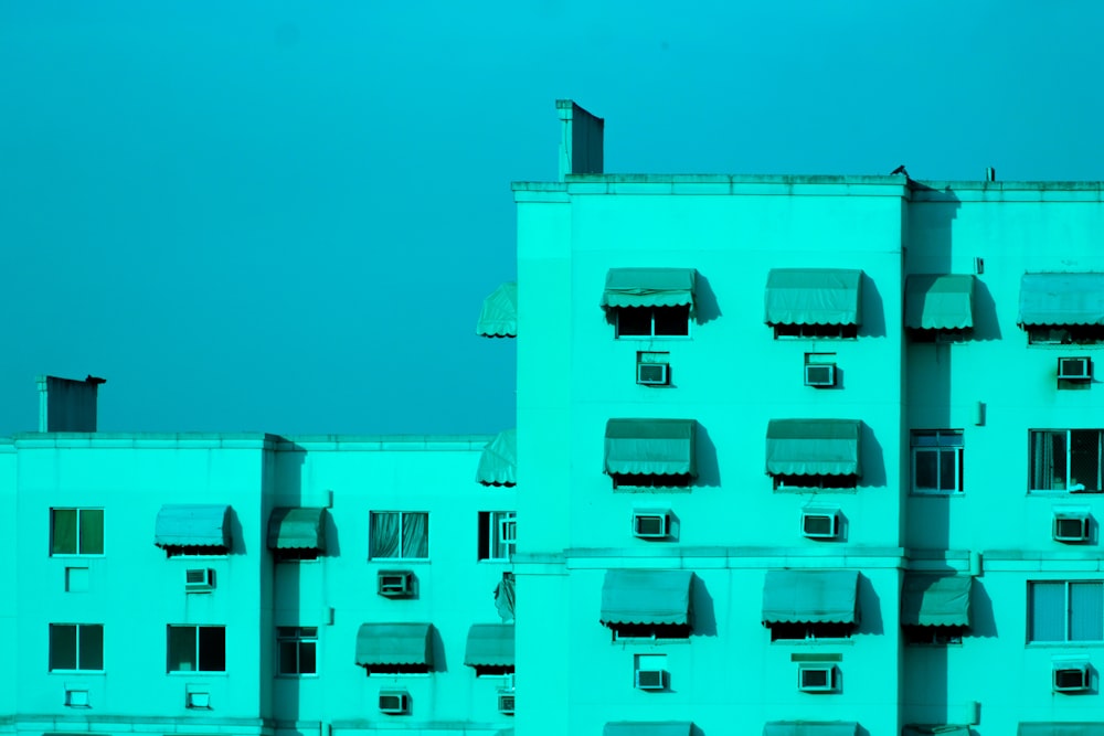 a tall white building with many windows and a sky background