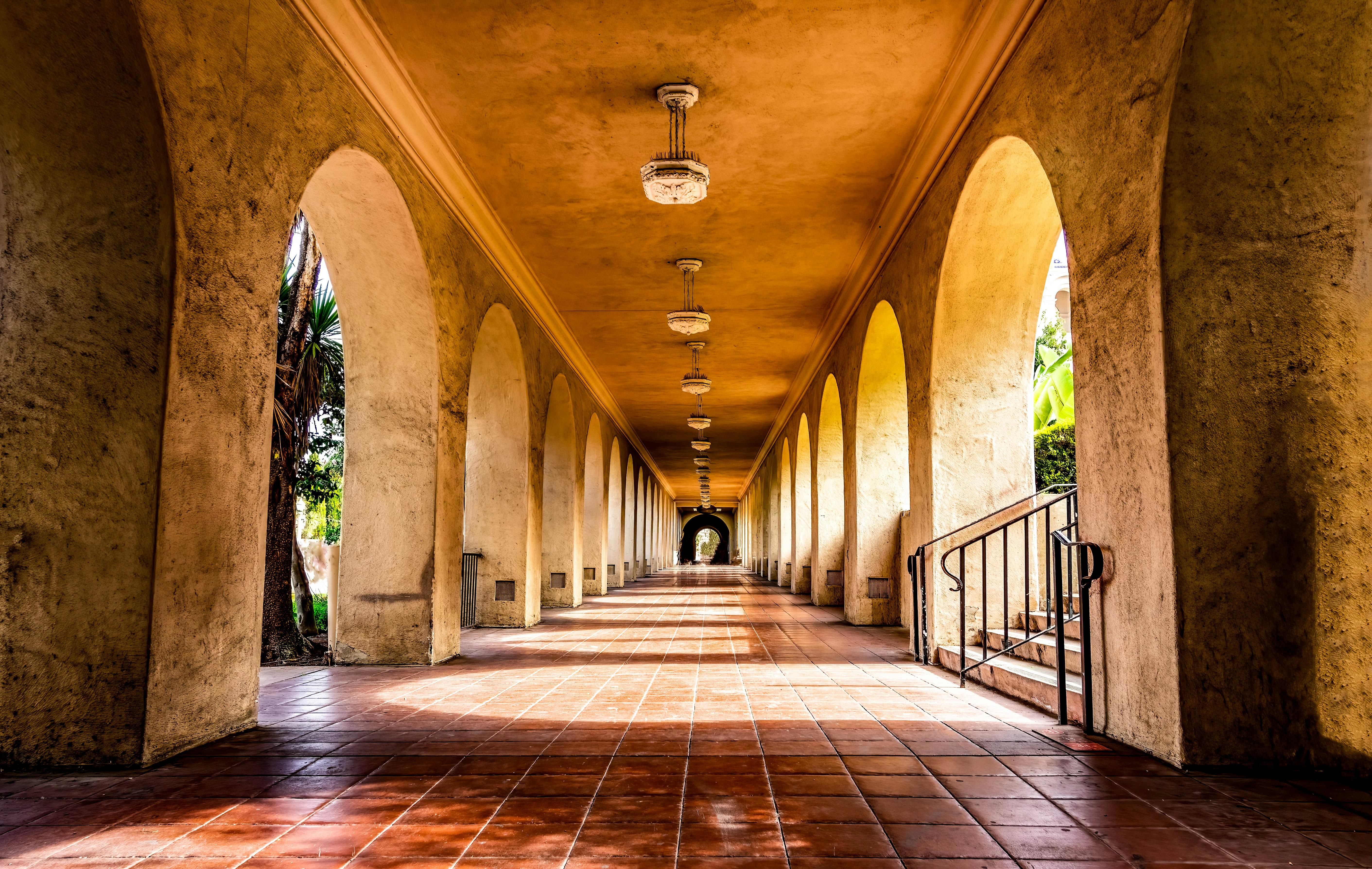 a long hallway lined with columns and lights, Arches at Balboa Park in San Diego