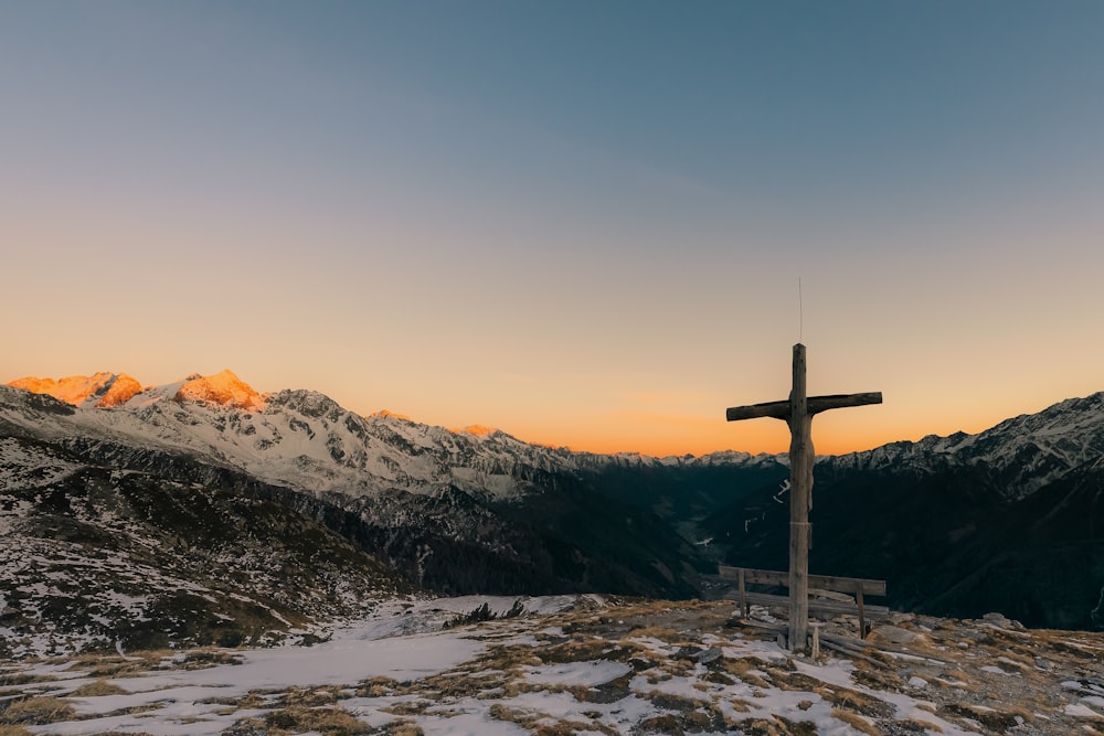 Una cruz en la cima de una montaña con montañas al fondo