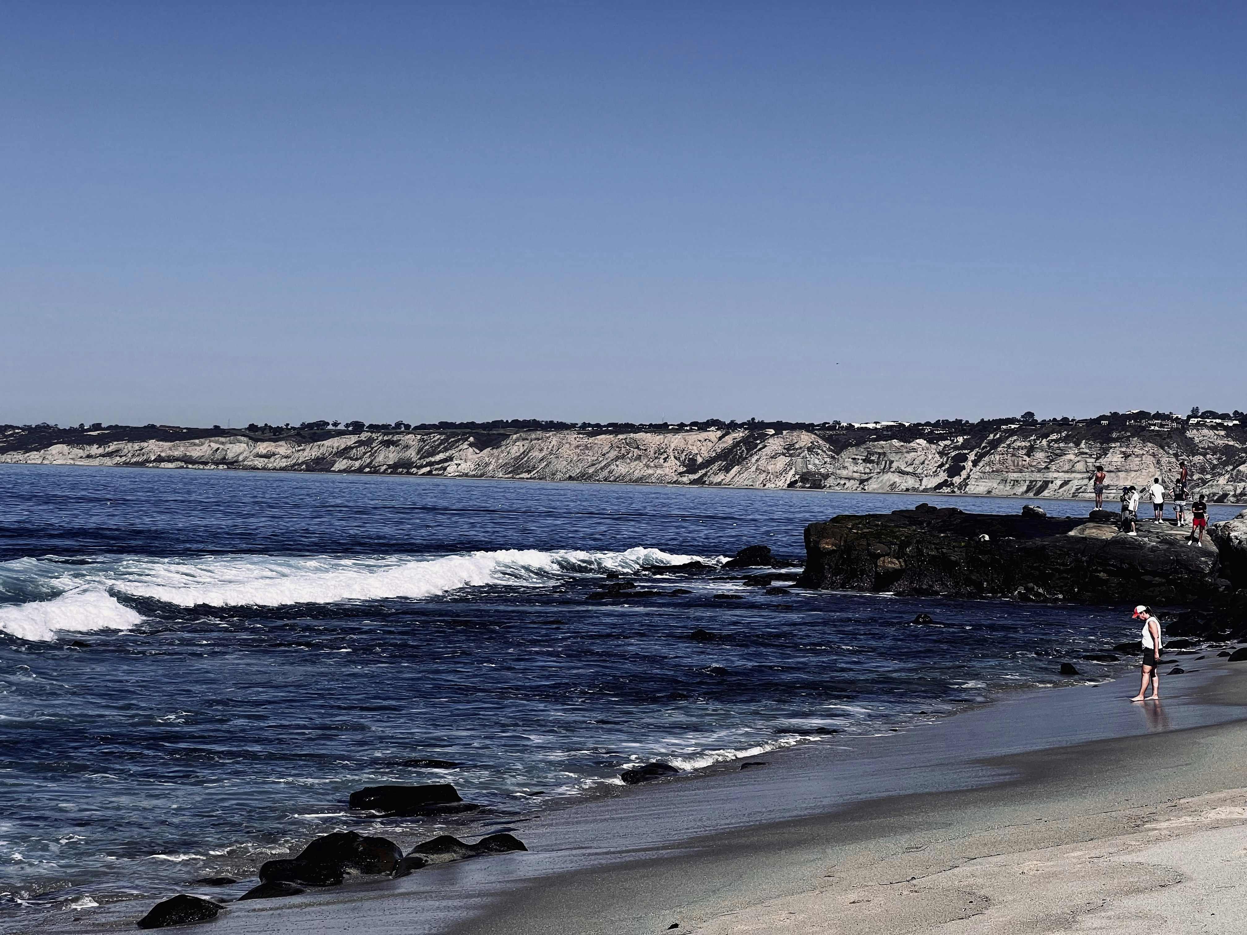a group of people standing on top of a sandy beach, 