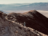 Hiker standing on a rocky outcrop overlooking a vast desert landscape.